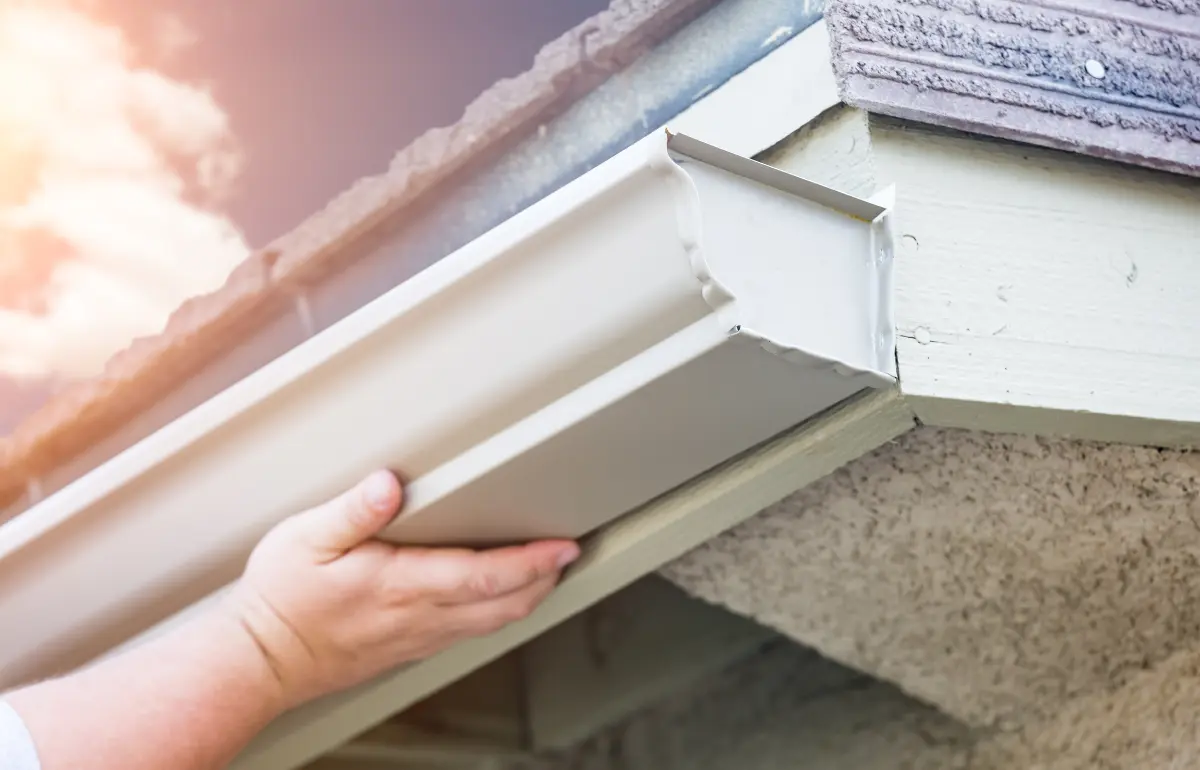 Professional seamless gutter installation crew fitting new aluminum rain gutters on a home